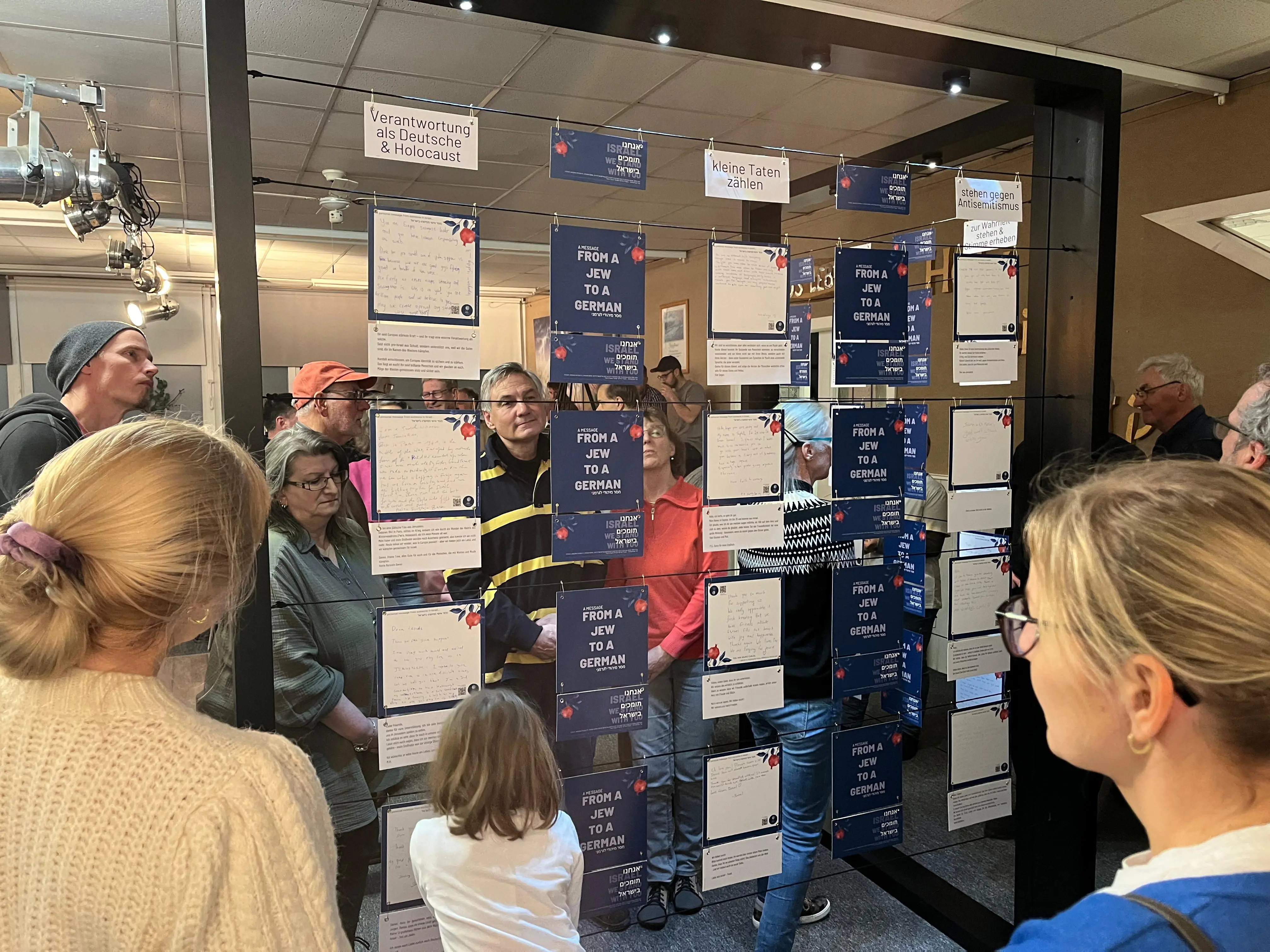 Besucher stehen vor der Ausstellung in Deutschland und lesen die aus Israel mitgebrachten Karten