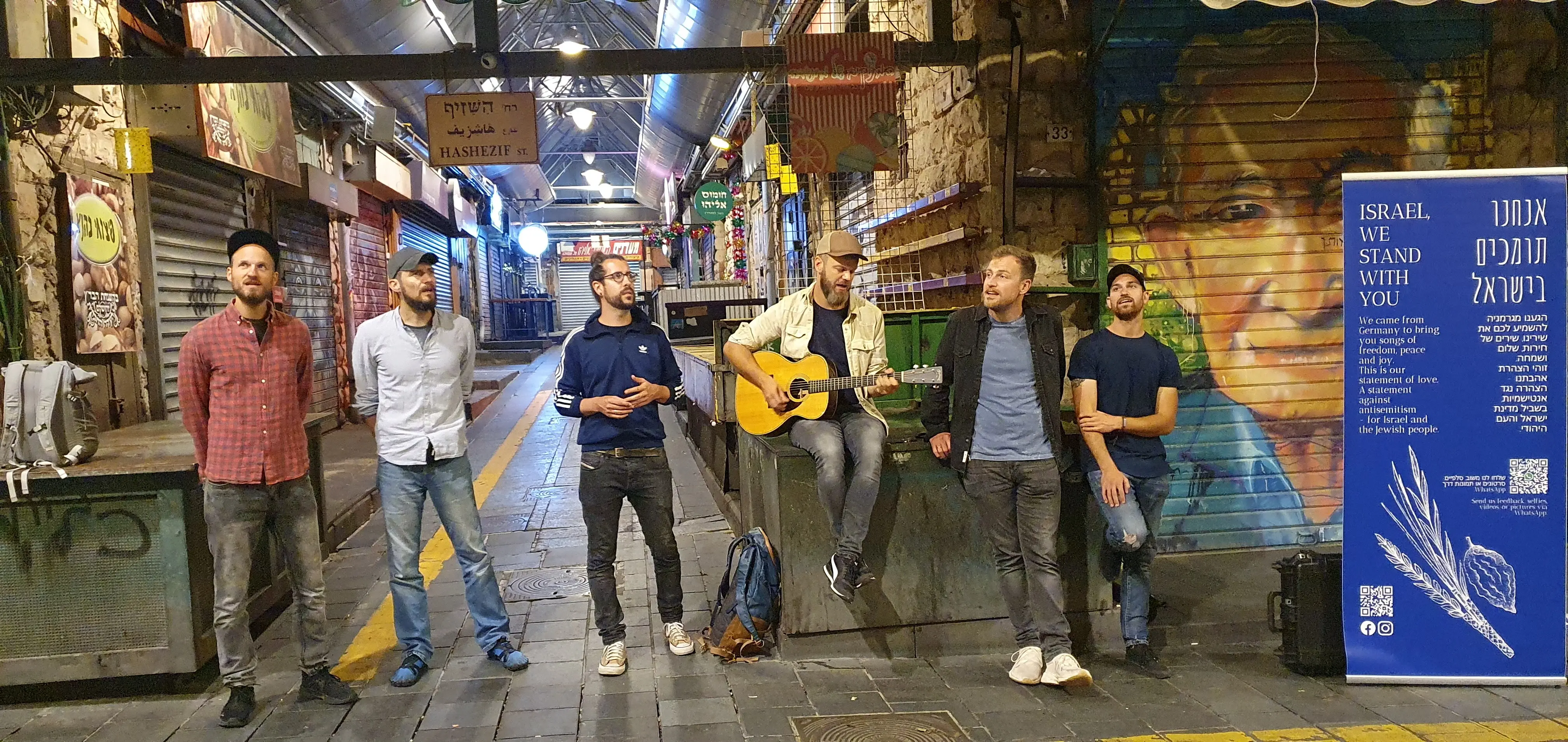 Sechs von uns im menschenleeren Markt von Jerusalem, die Läden heruntergelassen, daneben unser Banner