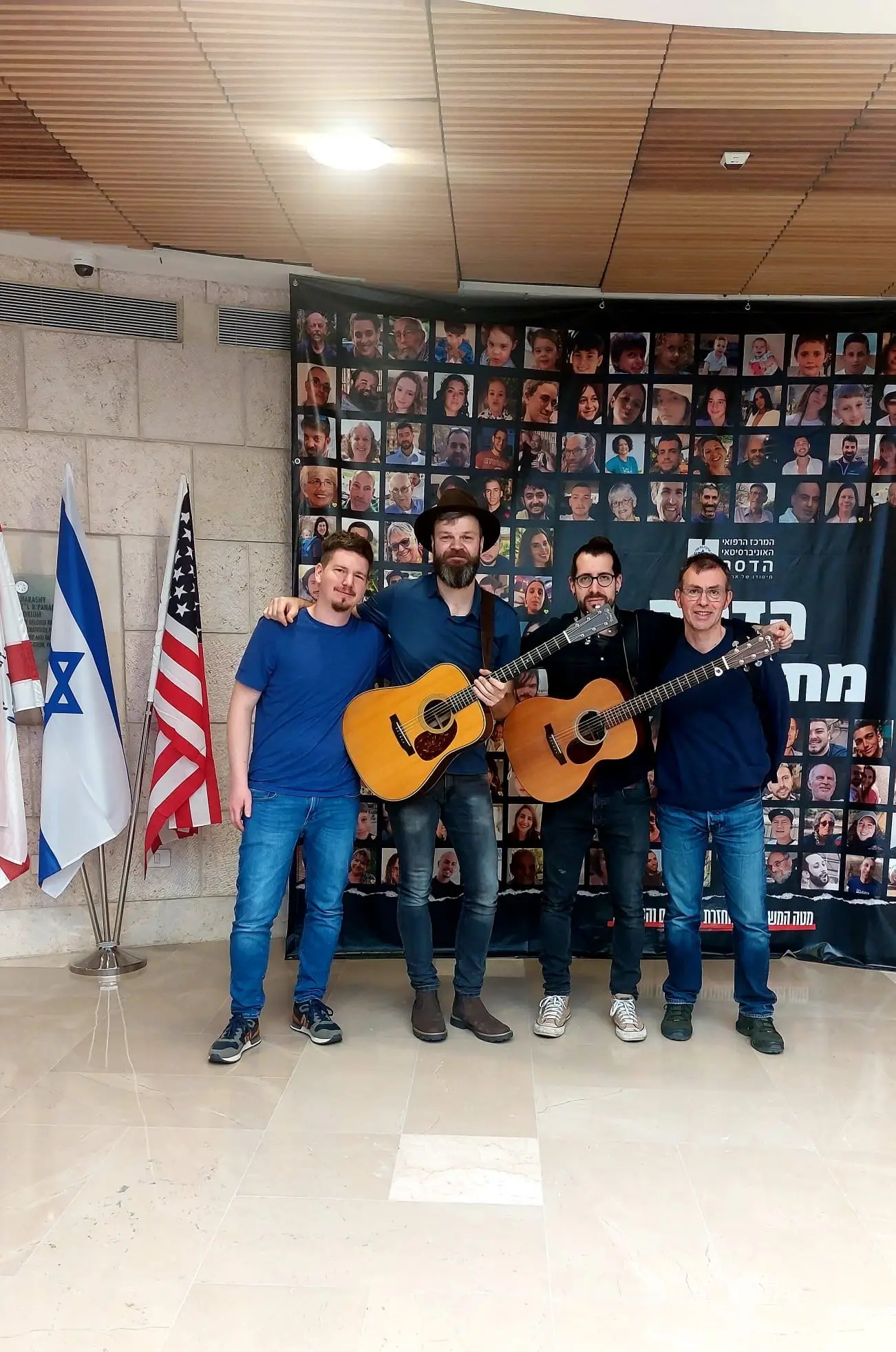 Vier Musiker unserer Gruppe im Februar 2024 vor einer Wand mit den Porträts der Geiseln