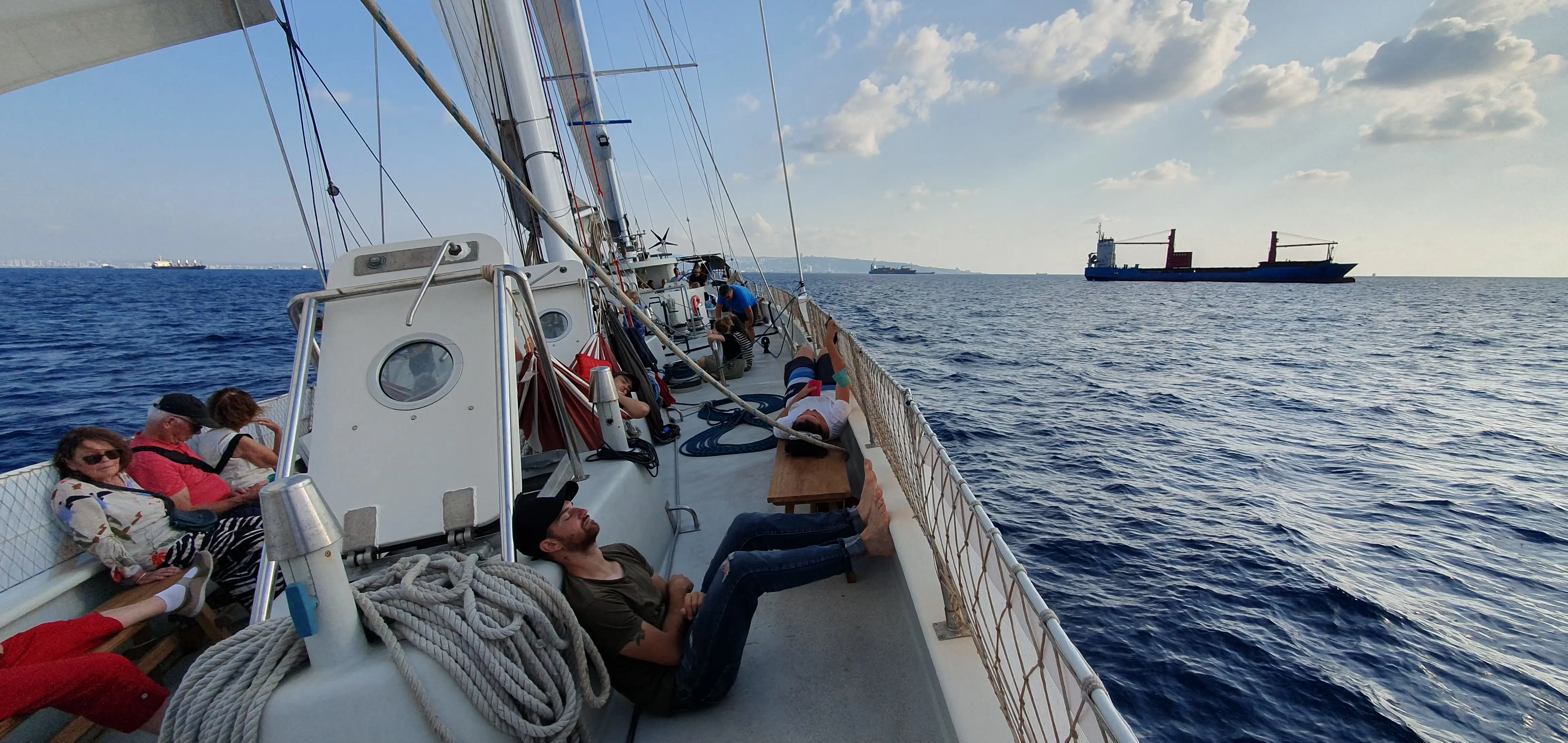 Blick über das Deck des Segelschiffs während der Überfahrt, ein Frachtschiff am Horizont